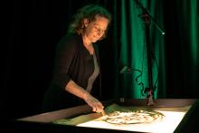 L'artiste dessine sur une table lumineuse avec du sable